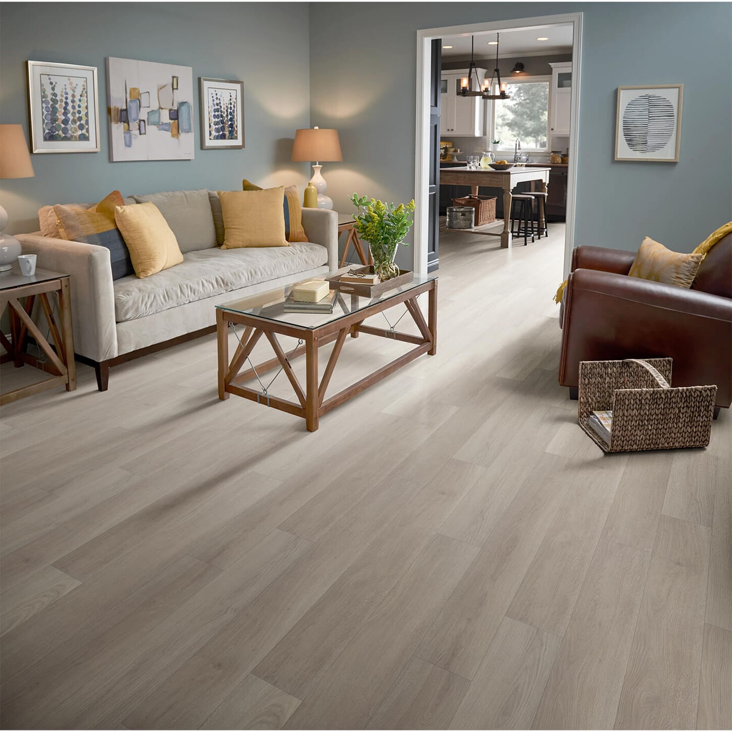 living room with light blue walls a tan sofa and a brown chair and the floor is a light wood look vinyl plank flooring