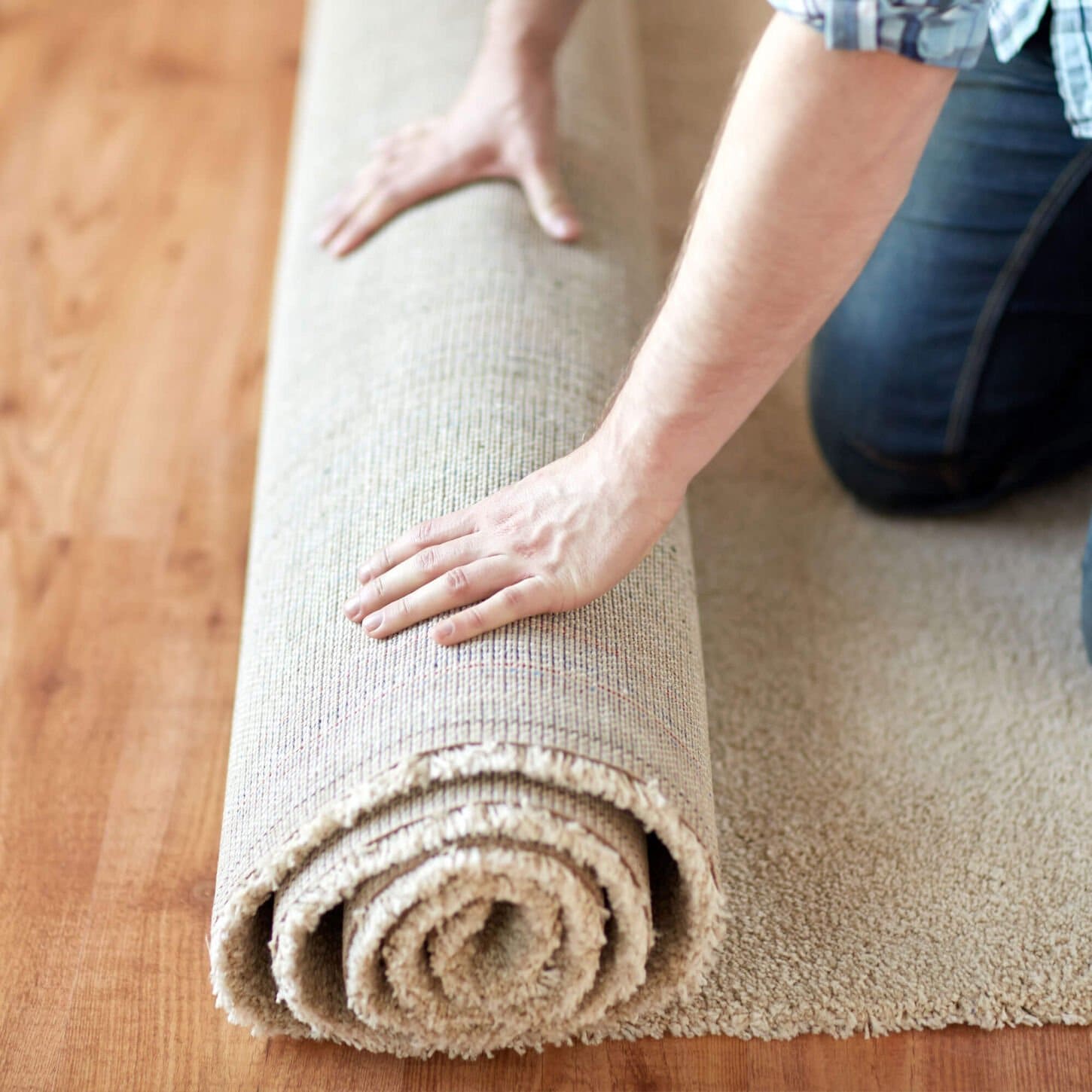 Person rolling out carpet over floor