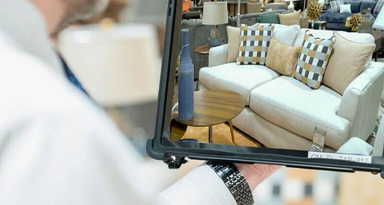NFM Salesman holding tablet showing customer furniture on sales floor