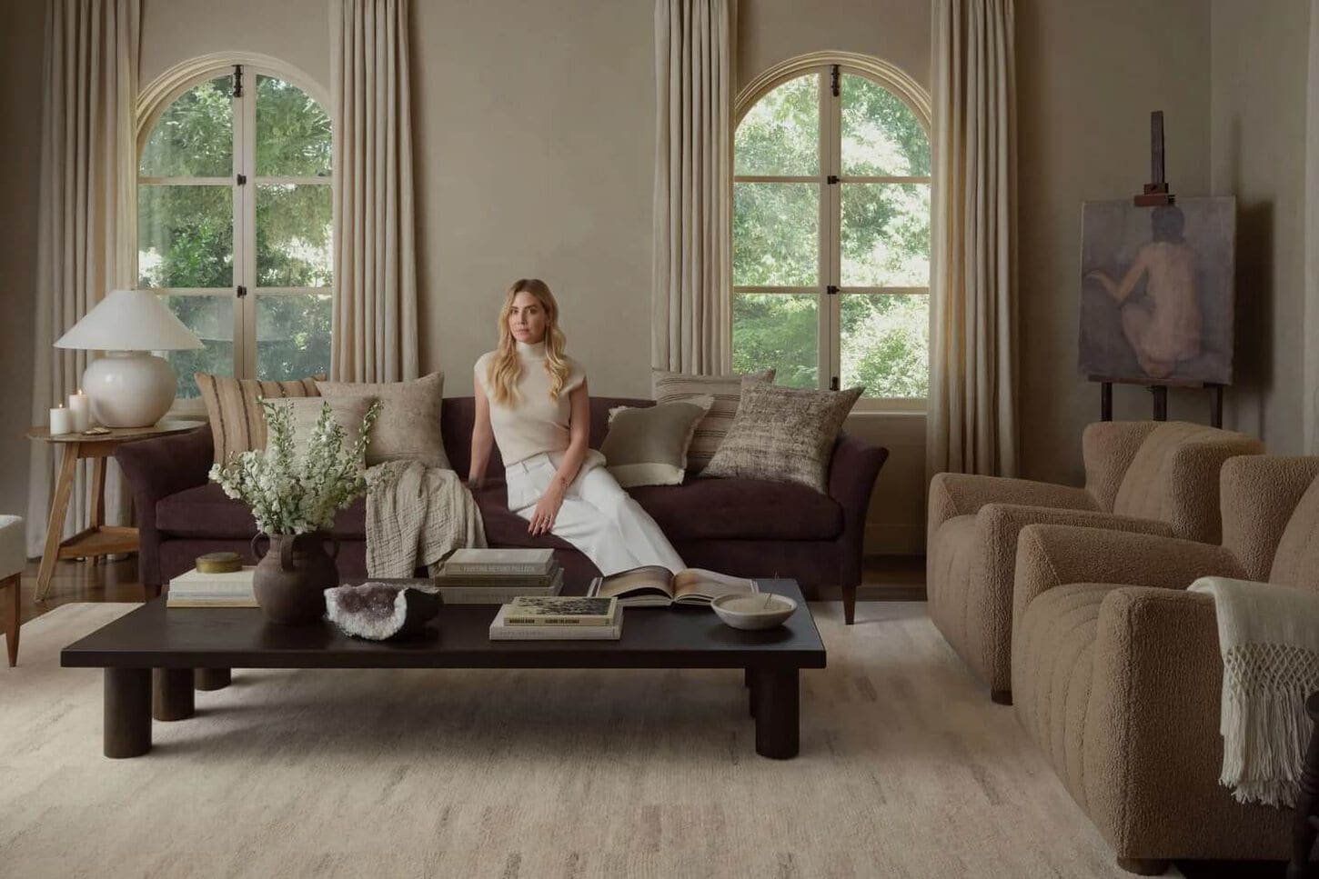 Amber Lewis in living room sitting on sofa with a large area rug and decor