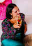 A young woman in a bright colored top happily celebrating with a strawberry champagne