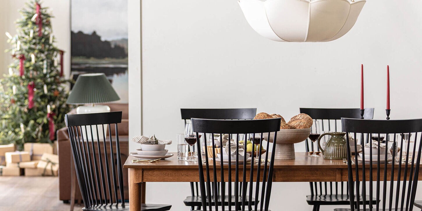 Dining room with large table, chairs, and a christmas tree in the background