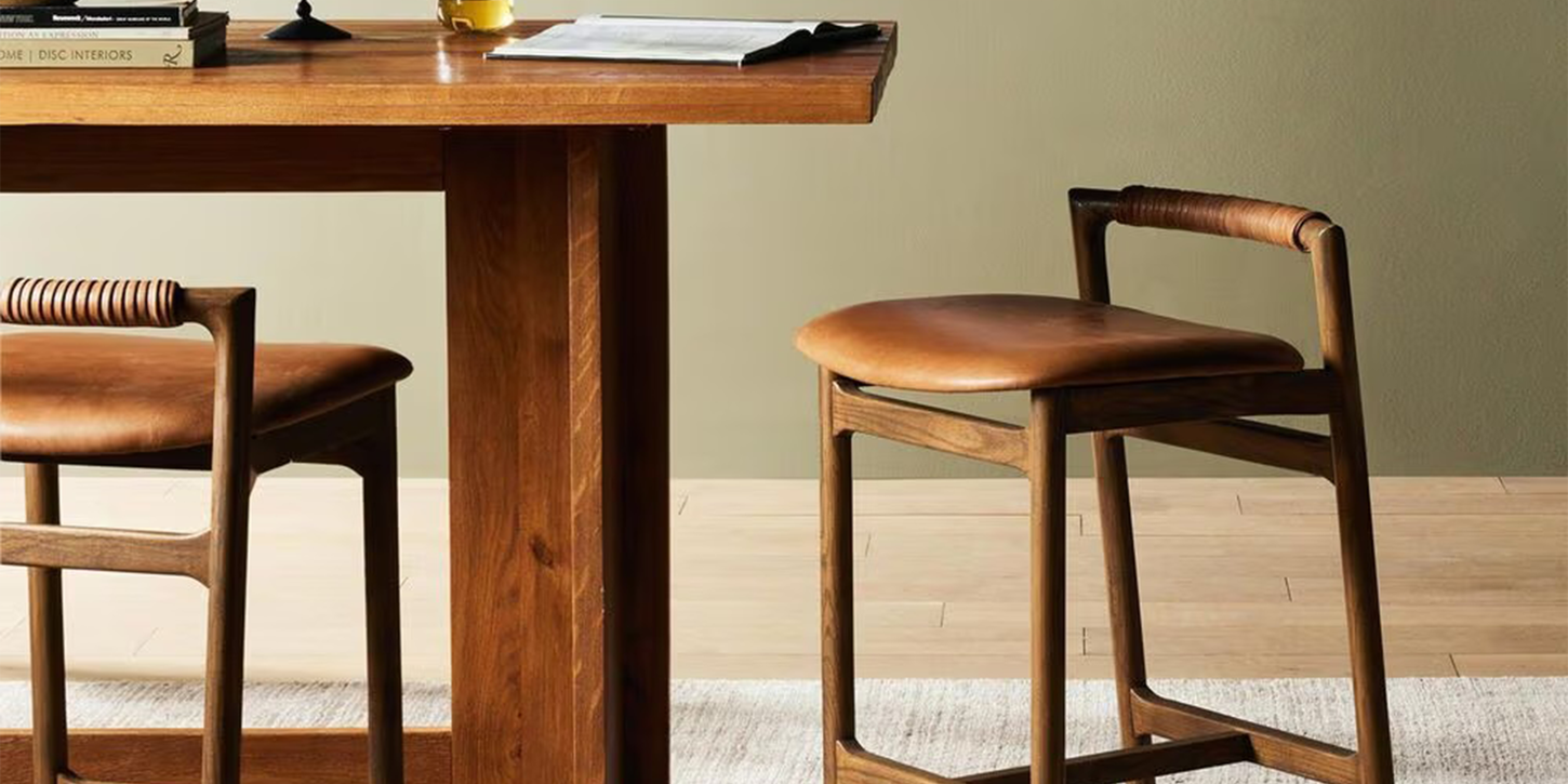 Wood and leather barstool in a dining room near a table with a rug