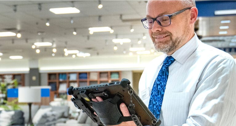 NFM Salesman holding tablet showing customer furniture on sales floor