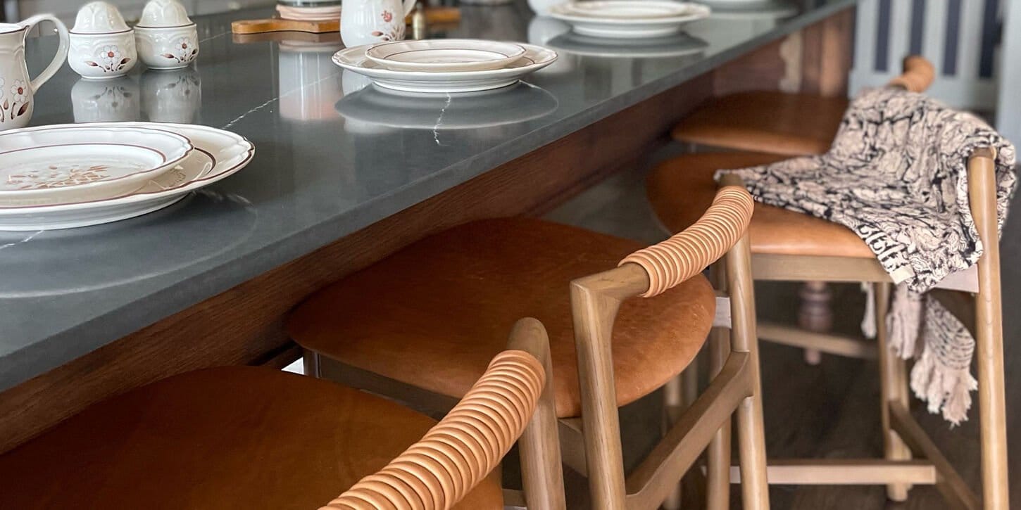 Wood and leather barstool in a dining room near a table with a rug