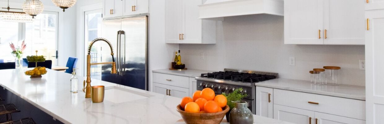 Bright kitchen with white granite countertops and modern white cabinetry with gold hardware accents.