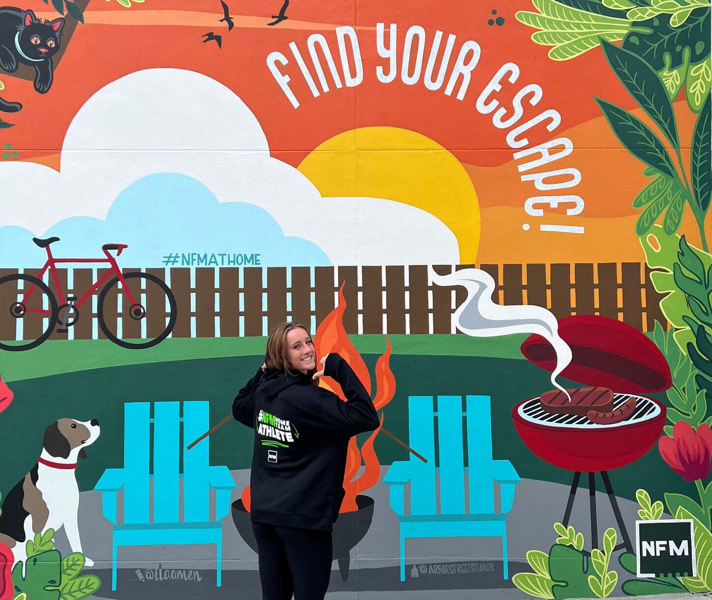 Jordyn Bahl with her NFM Home Team sweatshirt on in front of the NFM Mural
