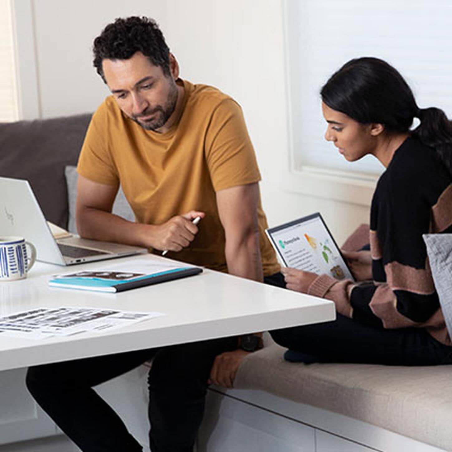 Two people sitting at table looking at HP laptop 