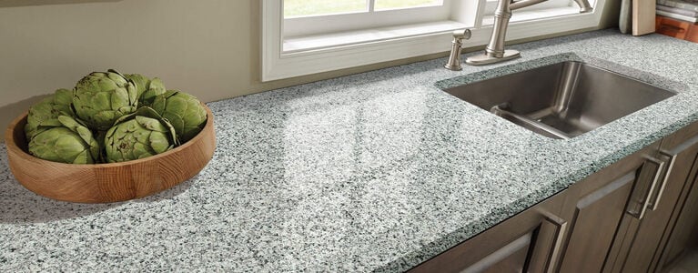 Granite kitchen countertop with artichokes displayed in bowl