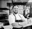 A headshot of Preston Paine crossing his arms in a kitchen. 