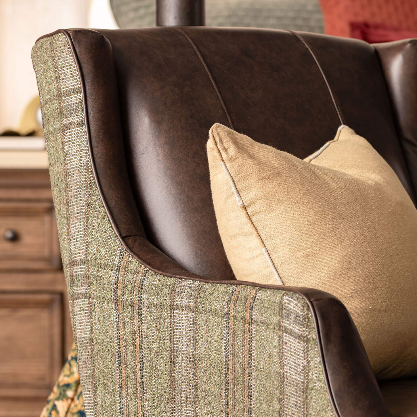 Leather accent chair in brown and plaid with yellow toss pillow.
