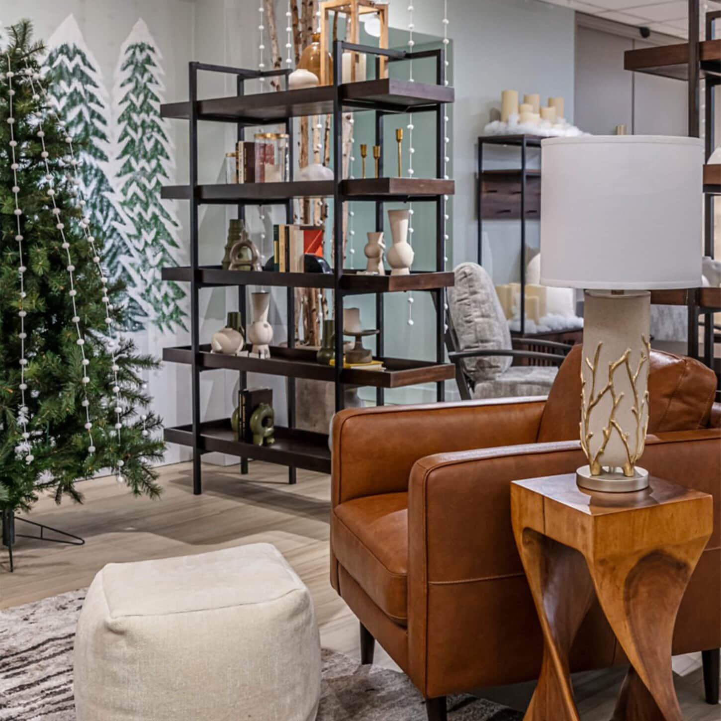 living room with tan arm chair next to a black and dark wood shelving unit with Christmas trees to the left