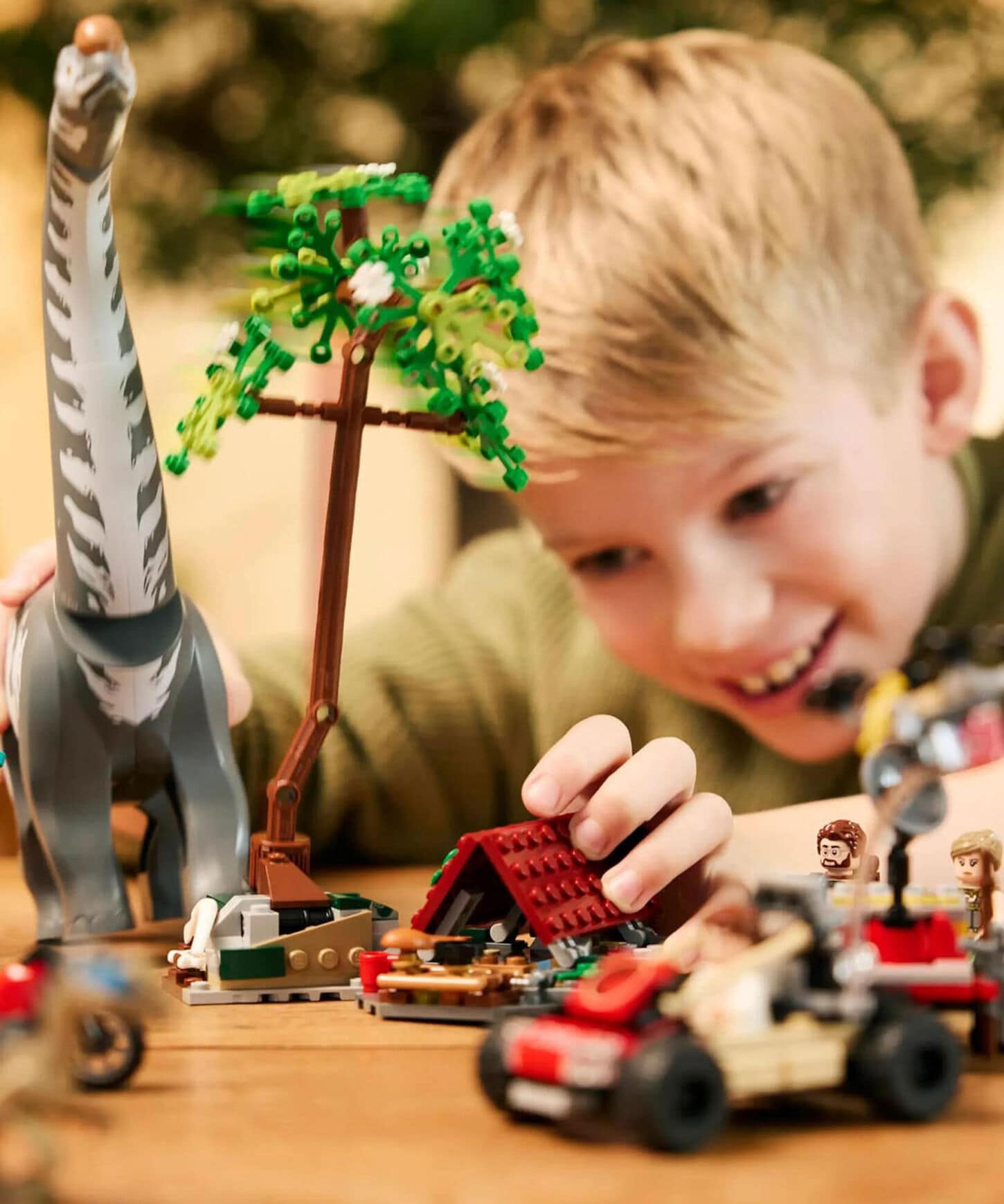young boy happily playing with a dinosaur lego set