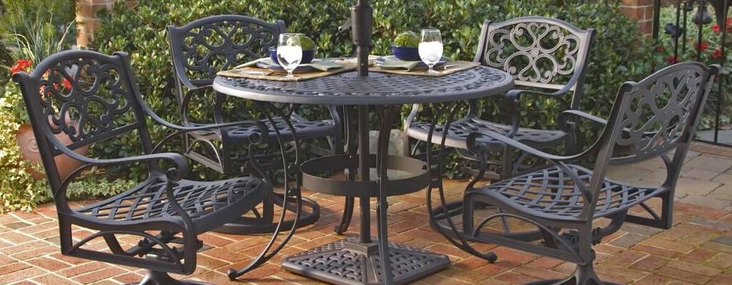 Ornate black metal patio set set on a red brick patio with brown shade umbrella