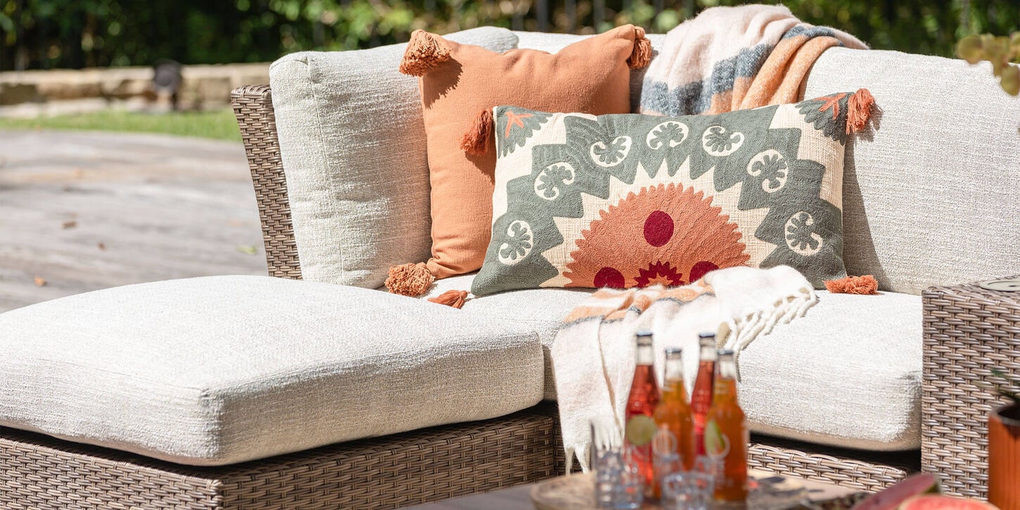 Outdoor patio furniture with pillows, a throw and drinks