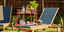 Outdoor pool furniture with a bar cart with drinks, flamingo, plant and radio