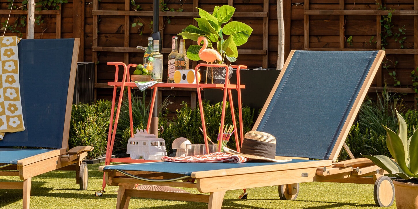 Outdoor pool furniture with a bar cart with drinks, flamingo, plant and radio