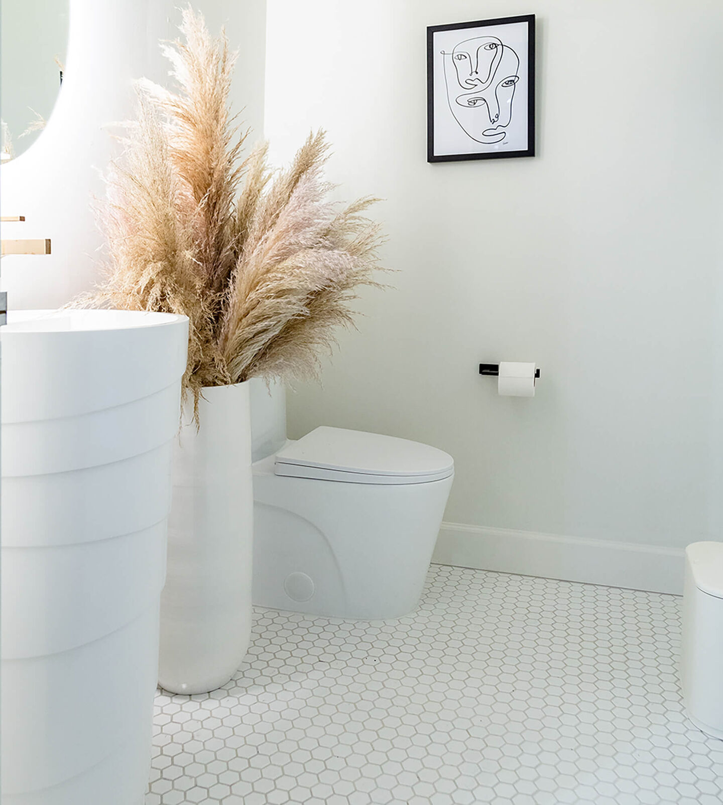 Earth toned bathroom with white hexagon flooring and Pampas grass as decor.