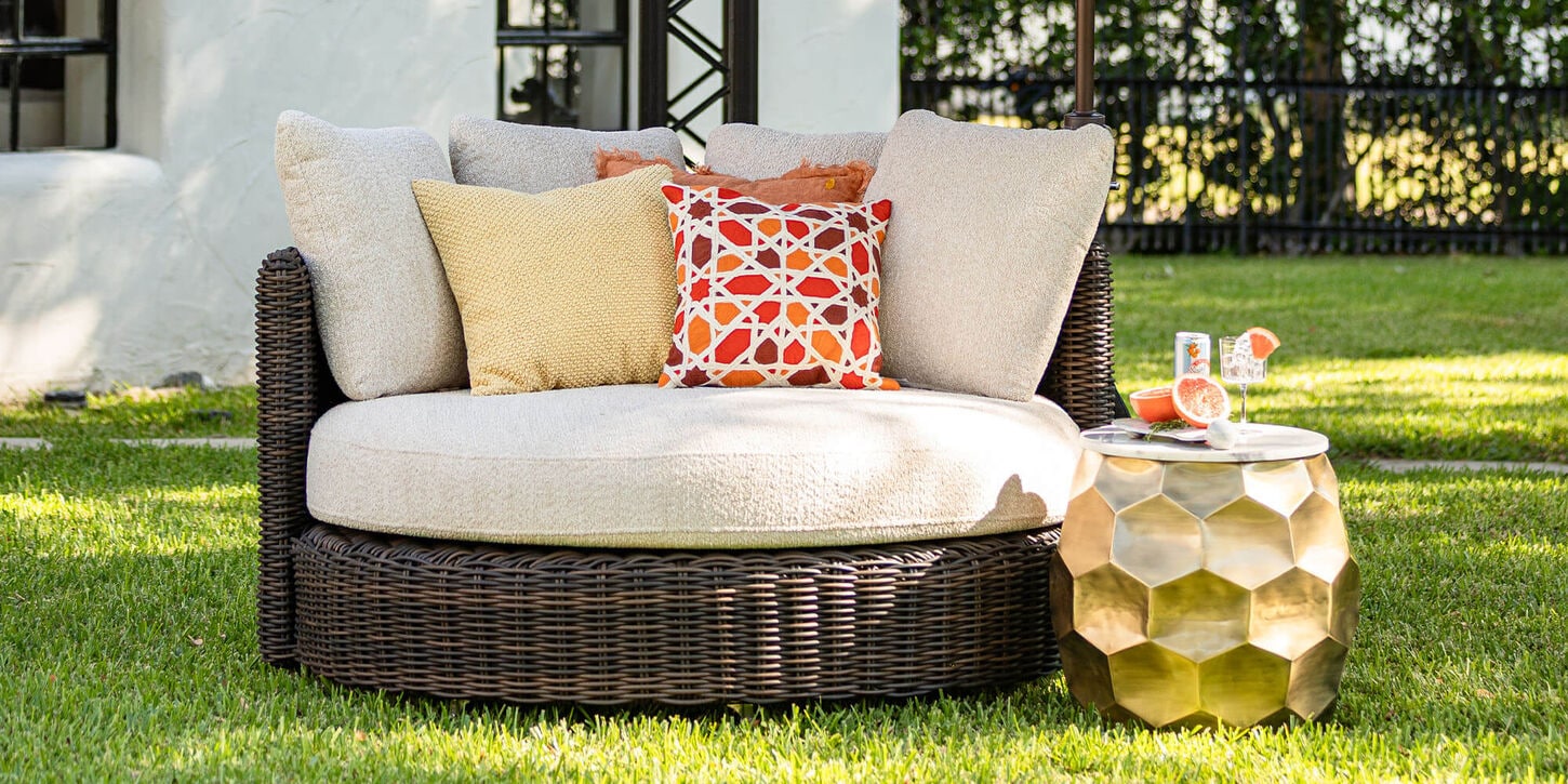 Outdoor oversized patio chair with throw pillows, and a side table with drinks in the backyard