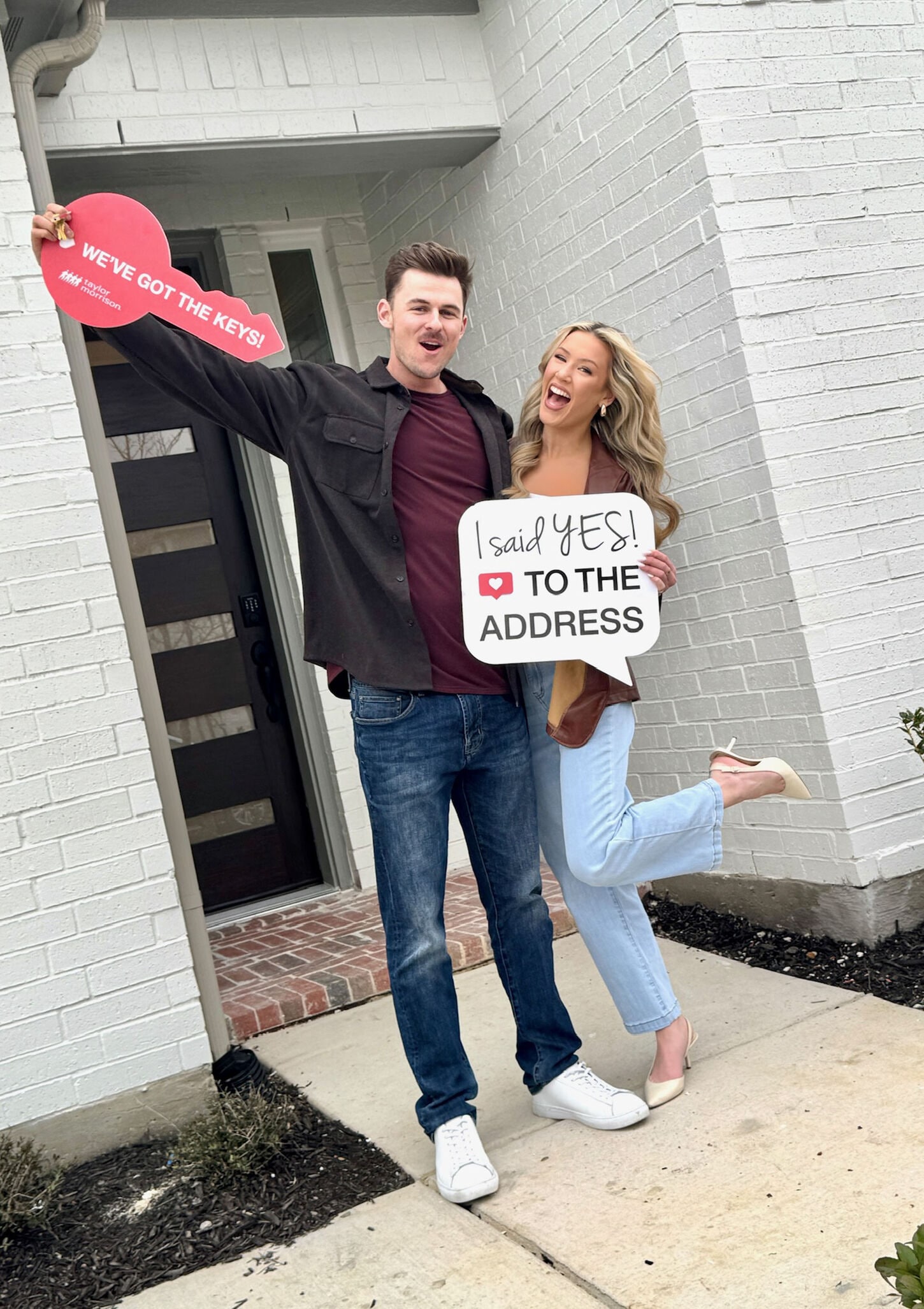 Influencers standing outside their home with signs 