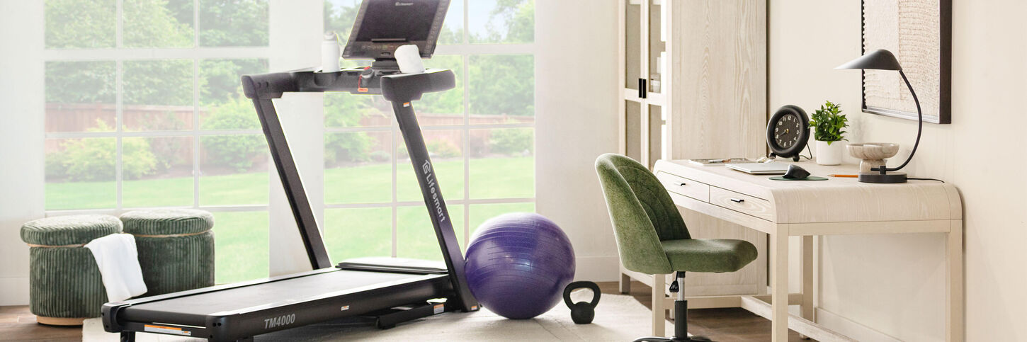 Room with a desk, chair, exercise ball, and a treadmill.