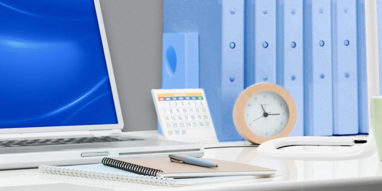 microsoft computer on a desk with a clock and binders