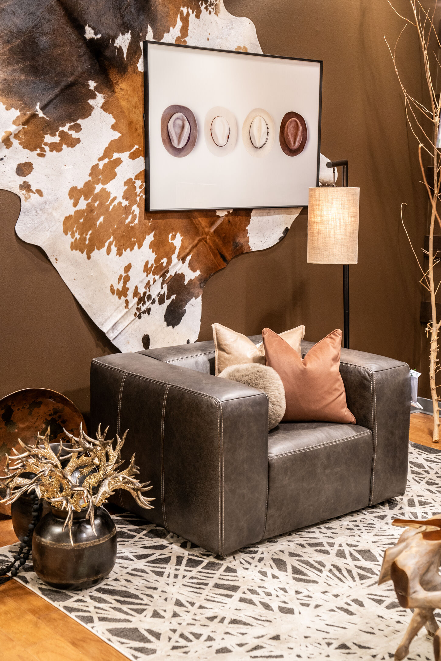 Dark room with cowhide rug, leather chair, and rustic/western decor