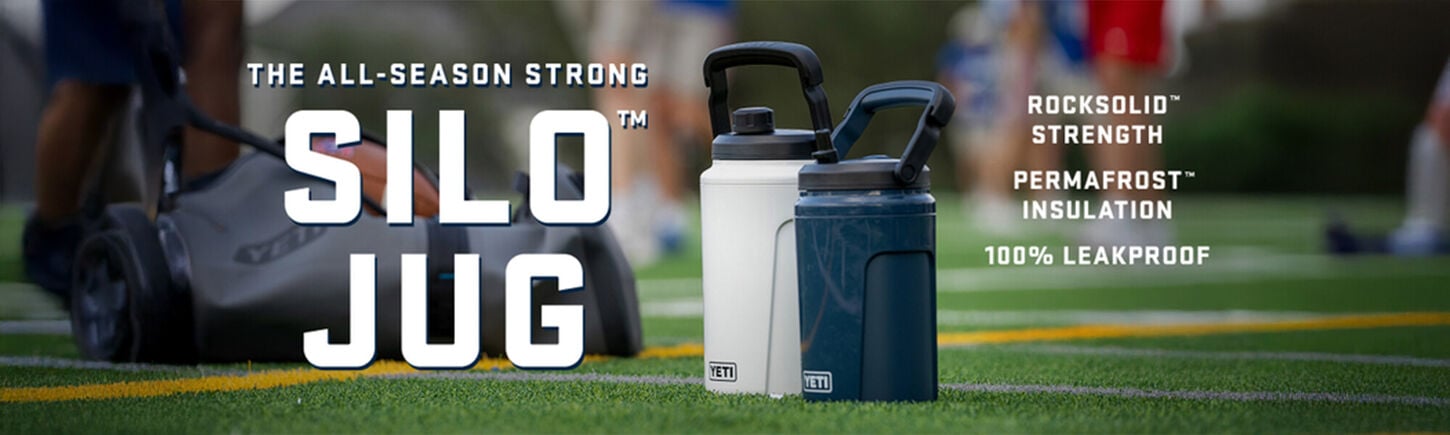 two yeti silo water jugs one white and one blue standing up on a green sports field