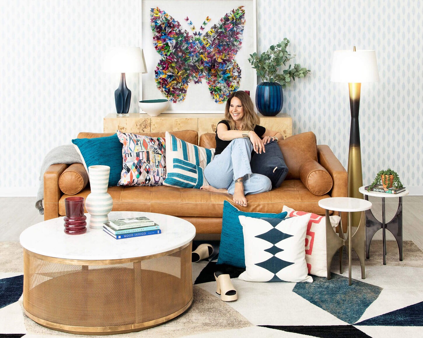Stacy Garcia sitting on Brown Leather sofa in colorful living room
