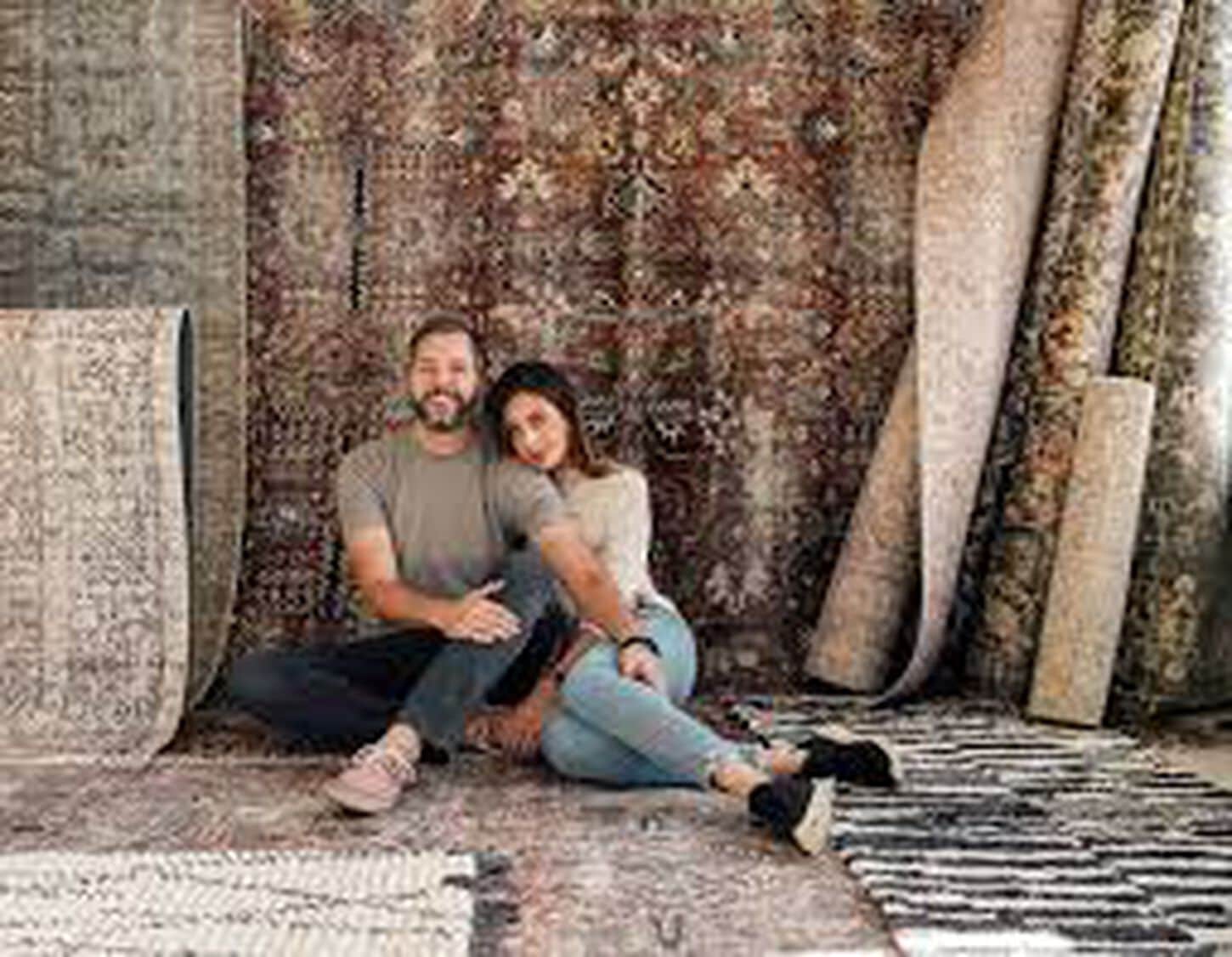 Chris and Julia sitting and posing near their rug designs