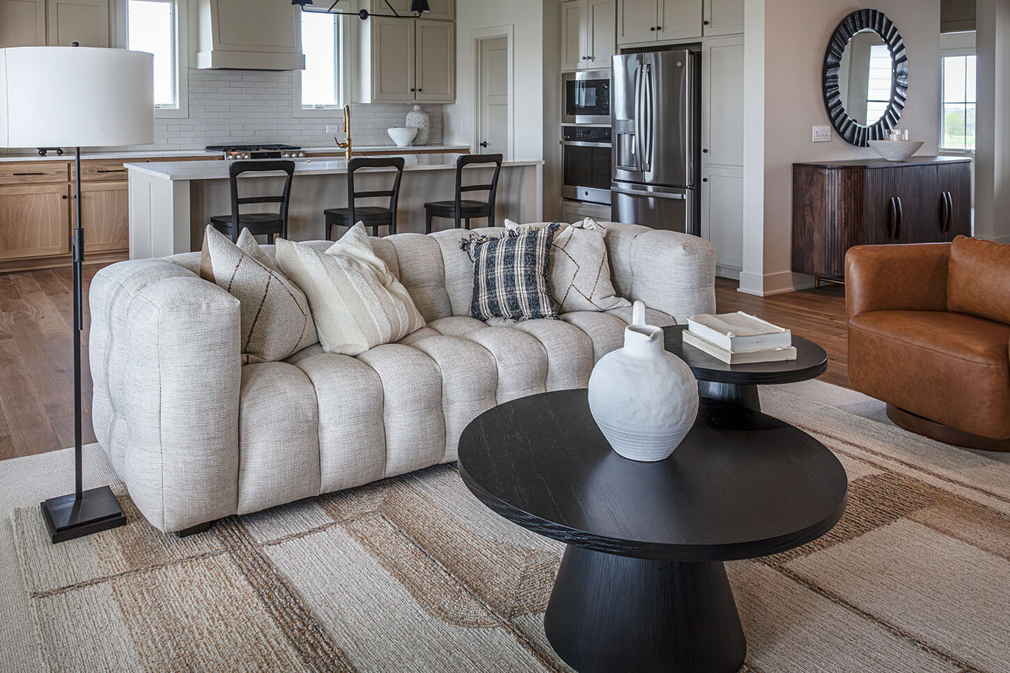 A well-furnished living space with two leather sofas, nesting tables, and a white sofa. 