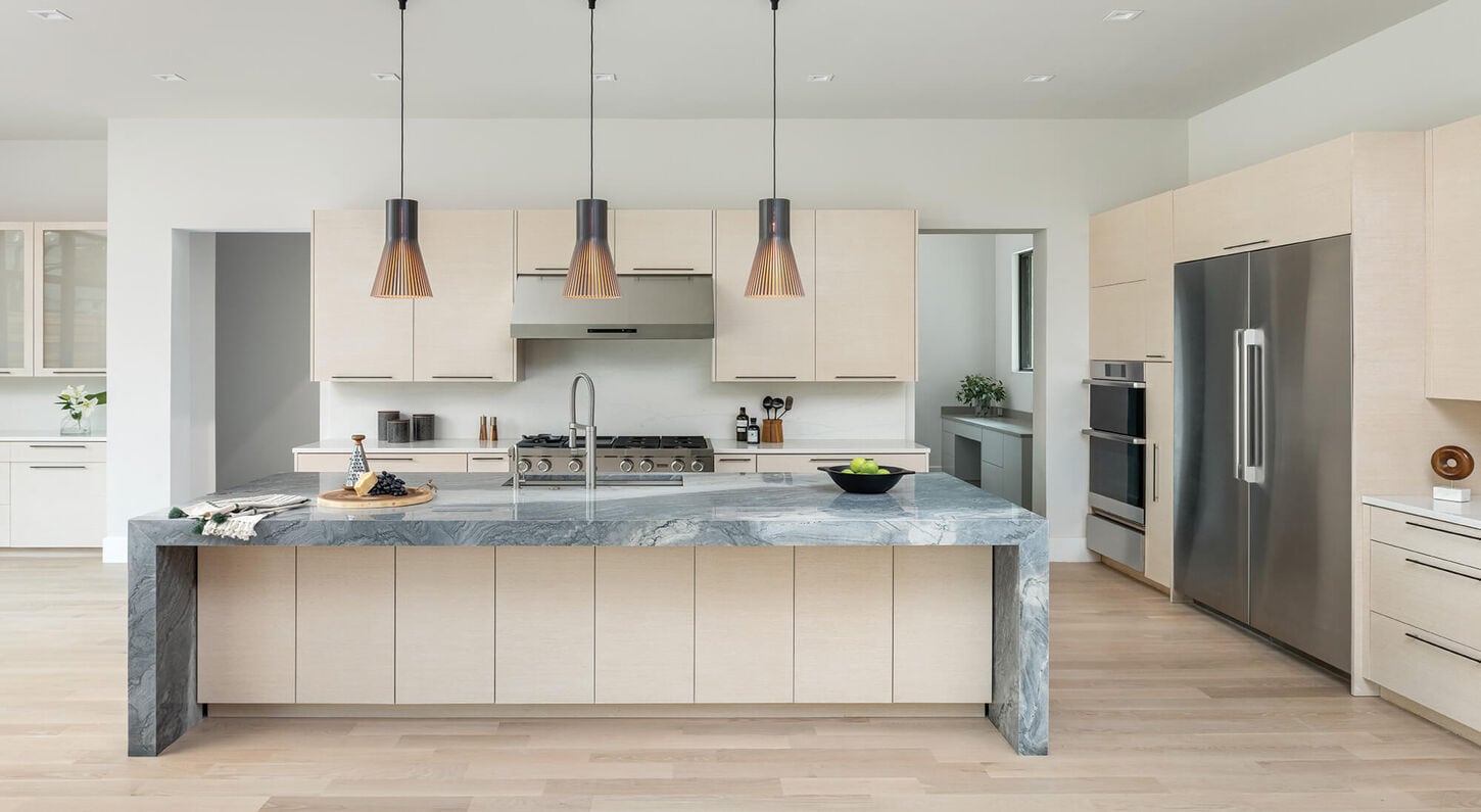 A white kitchen with bold pendant lighting above the island of the kitchen.
