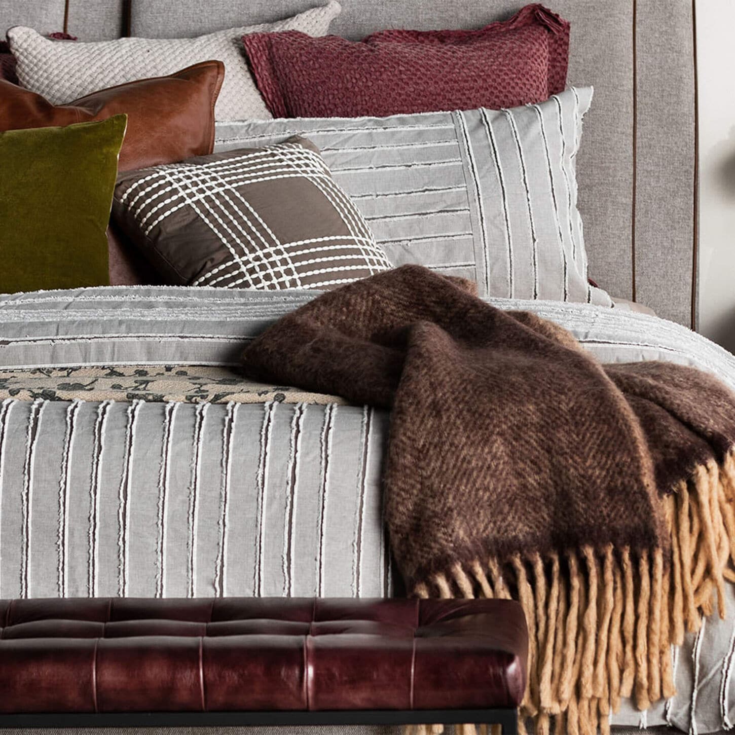 Fall vibe bedding featuring darker shades and more blankets in our Influencer's room with a lamp on the in background