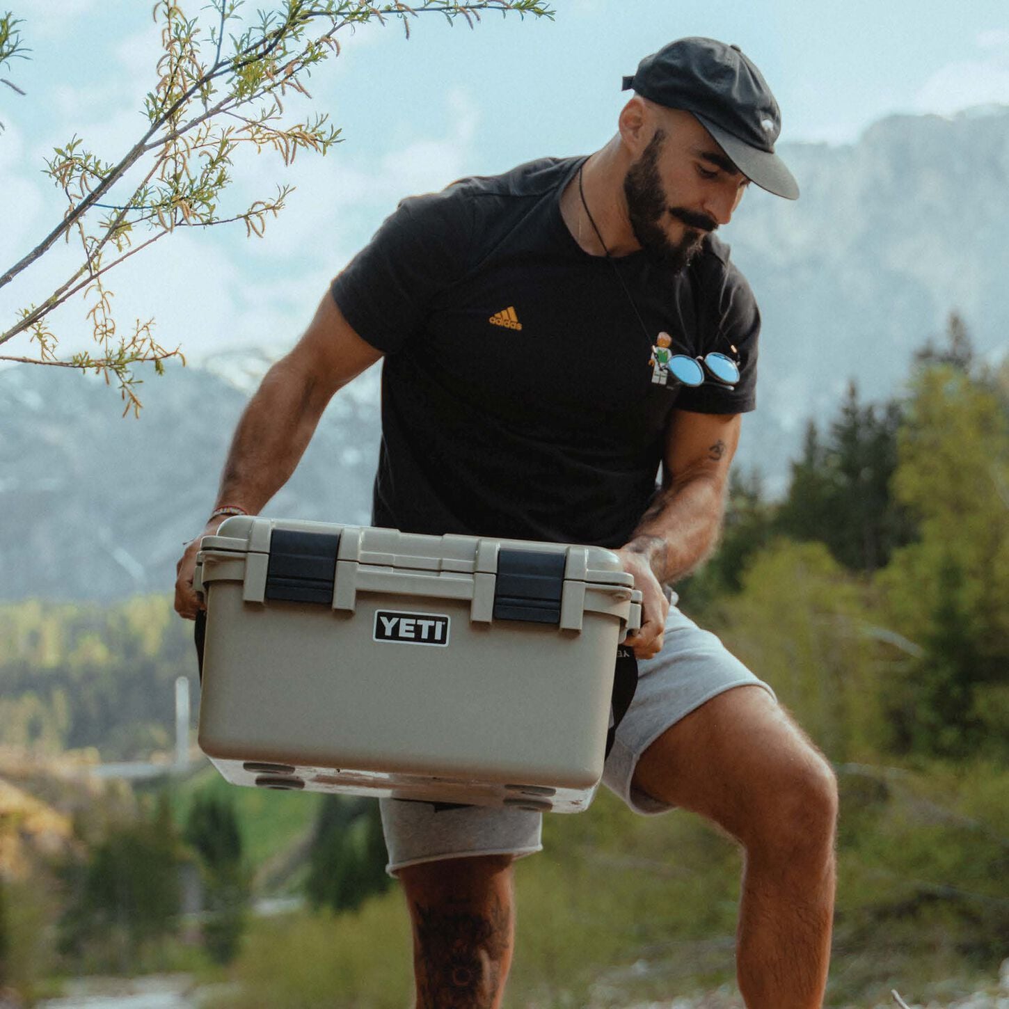man holding a white yeti cooler in an outdoor scenery