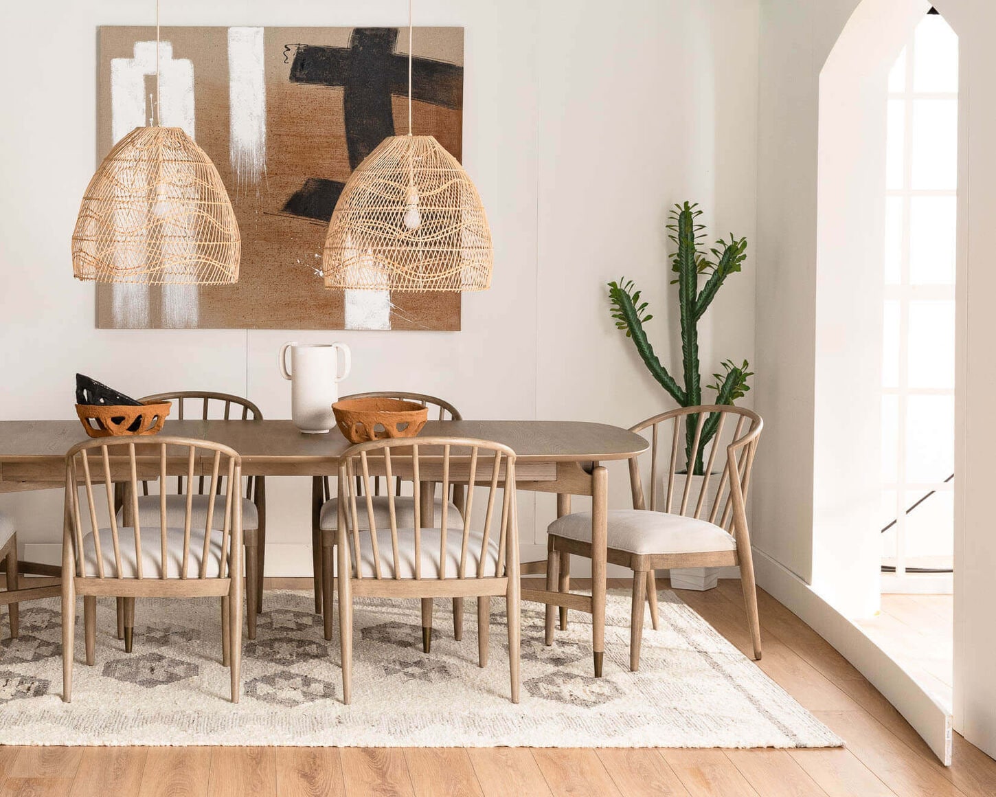 Dining room with a rustic vibe including a dining table and chairs, cactus, painting, rug, and light fixture