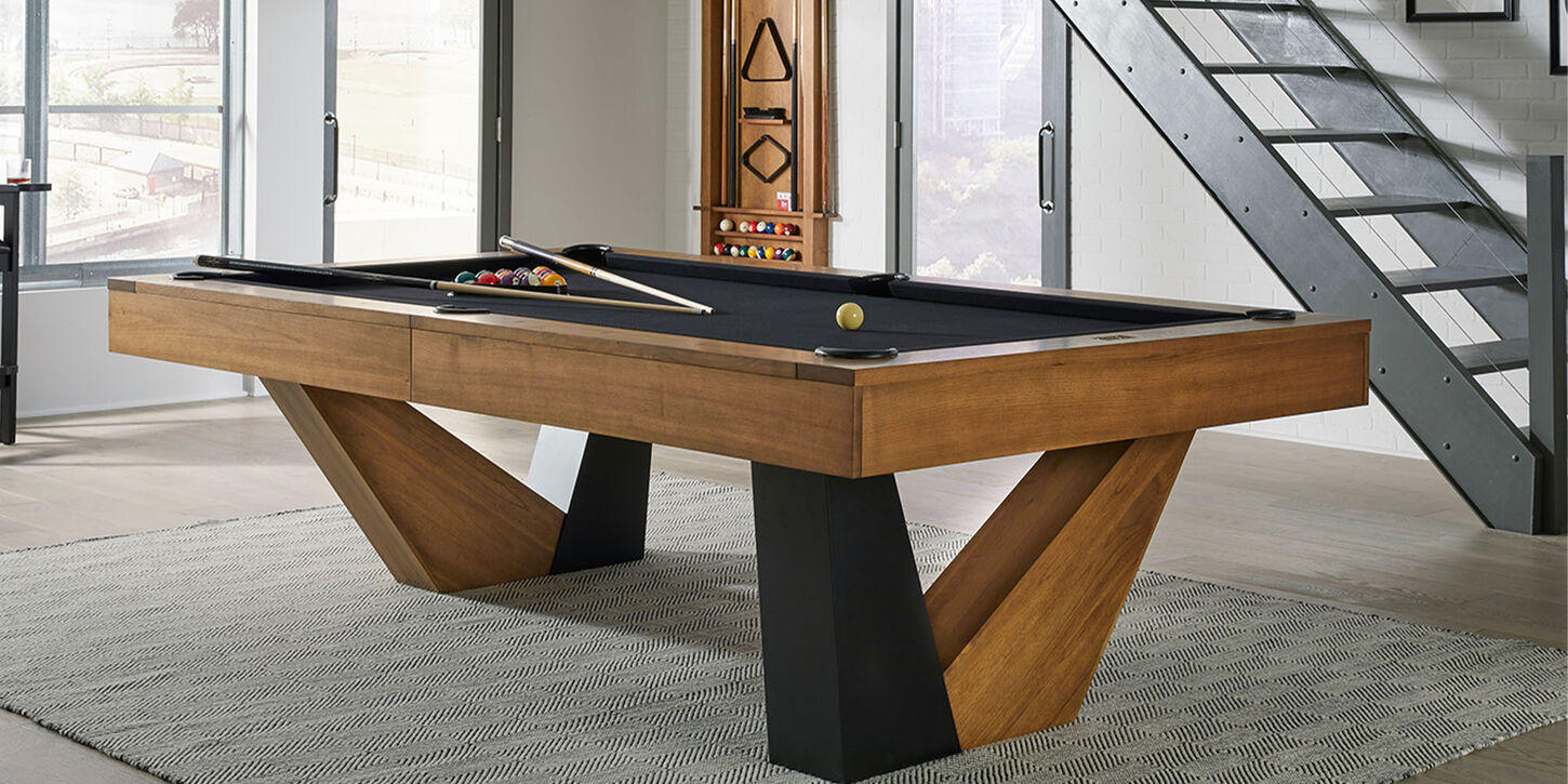 pool table on top of a rug inside a home next to modern stairs