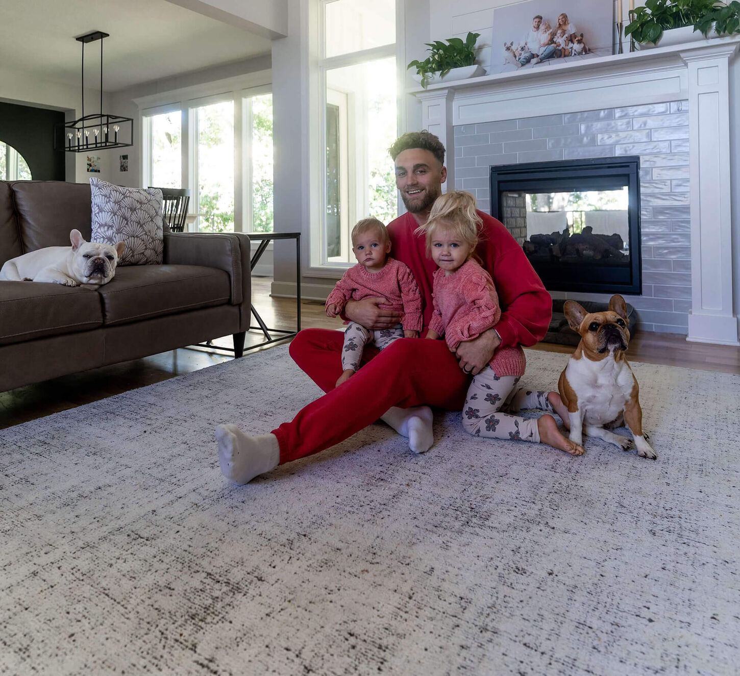 Gehrig Dieter with two kids and two dogs sitting on living room rug