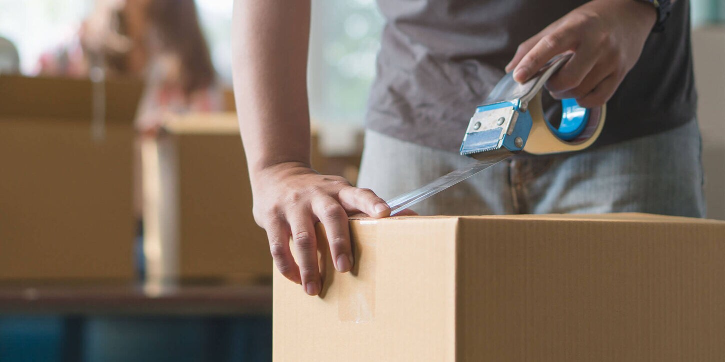 Man packing boxes and taping up a box with tape
