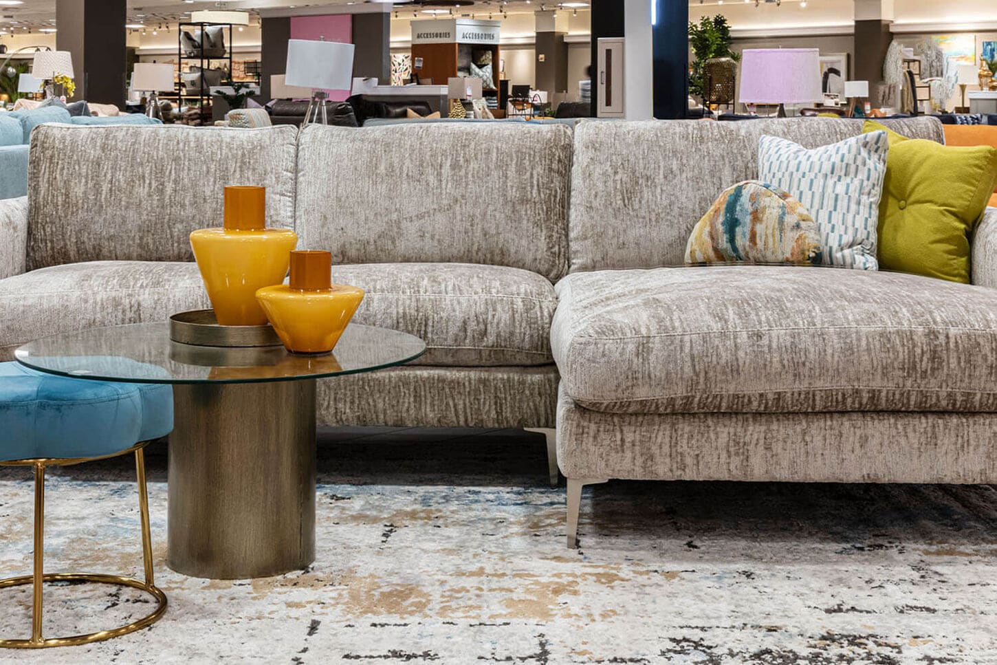 Gray couch with various throw pillows, coffee table and candles inside NFM store