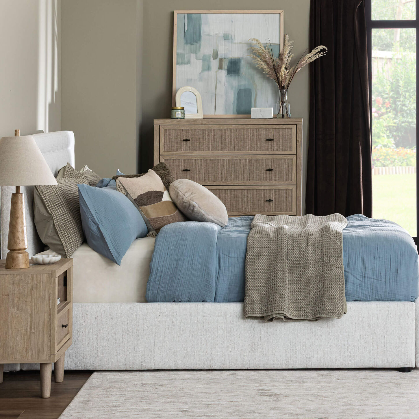 A white fabric bed fully decorated with pillows and blankets 