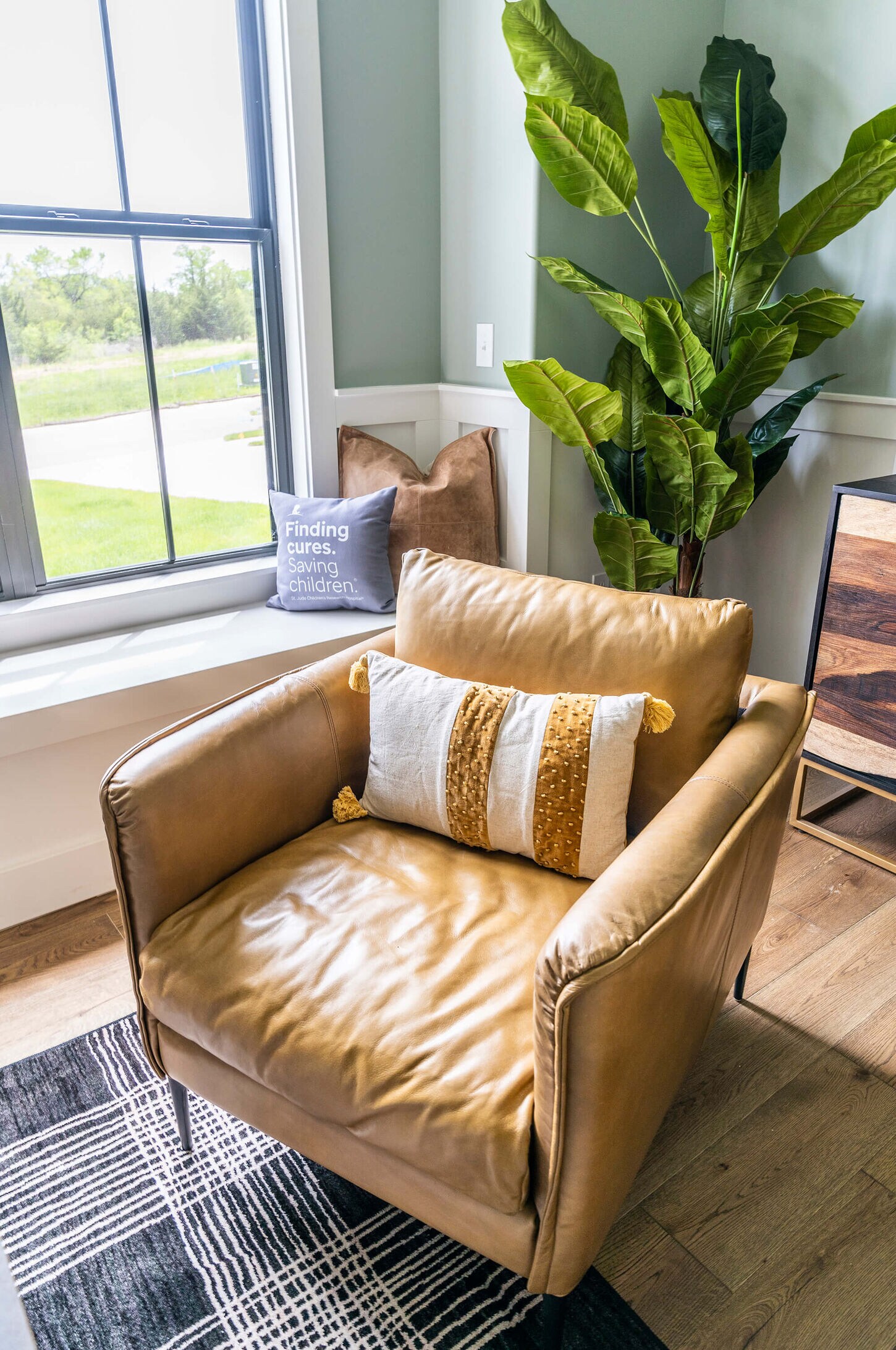 living room leather chair with a window and green plant in the background