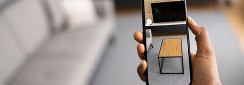 Hand holding smart phone with AR furniture in view finder