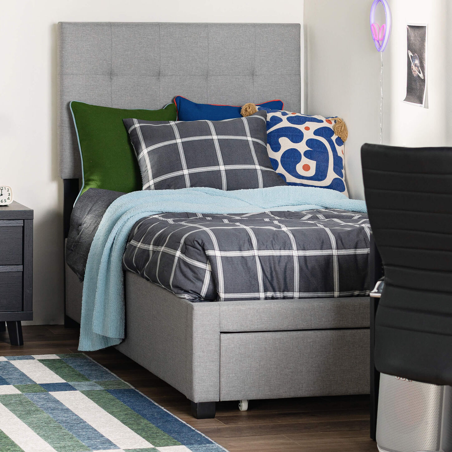 Bed with gray comforter and blanker in a dorm room