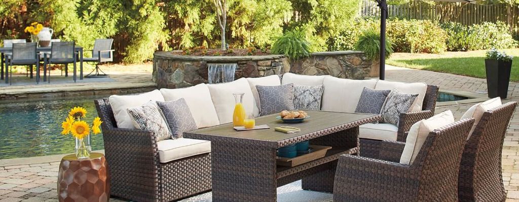 Backyard lanai with sectional and chair in dark brown and beige with light tan shade umbrella