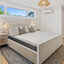 A cozy bedroom with a mattress nightstand, and a light-filled window.