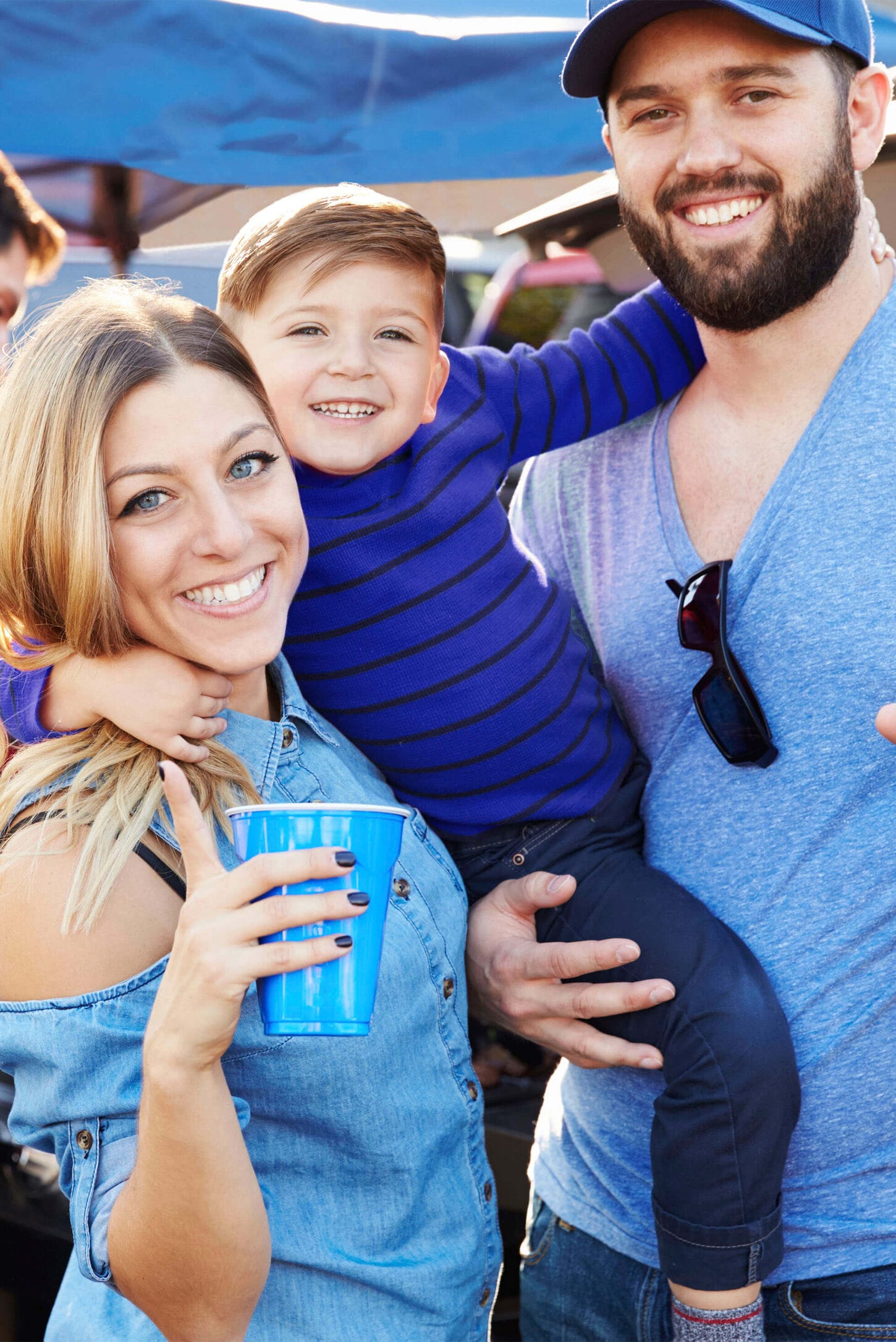 Family at tailgate party with husband, wife and child smiling for the photo