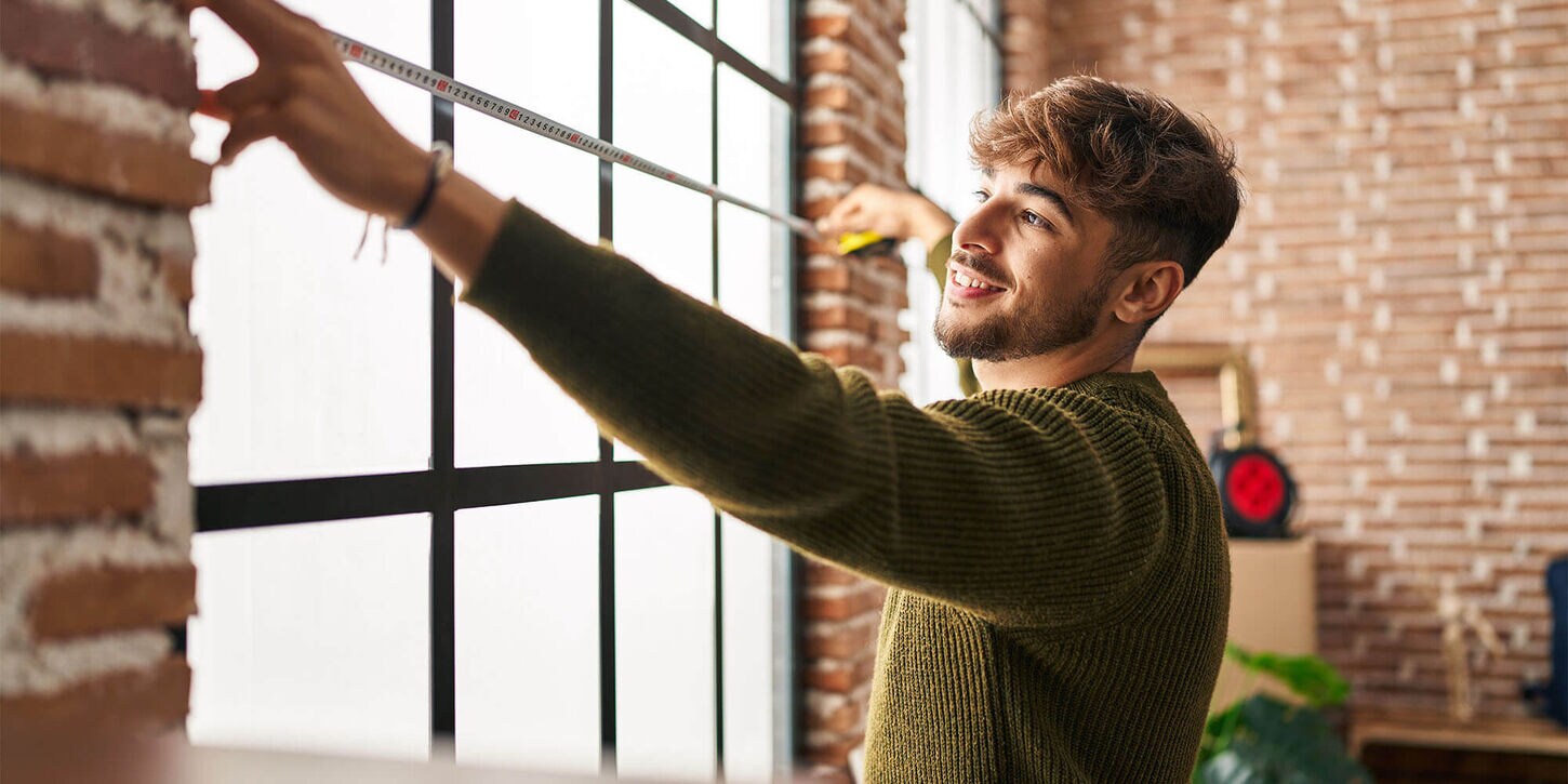 Man measuring a window using a tape measure