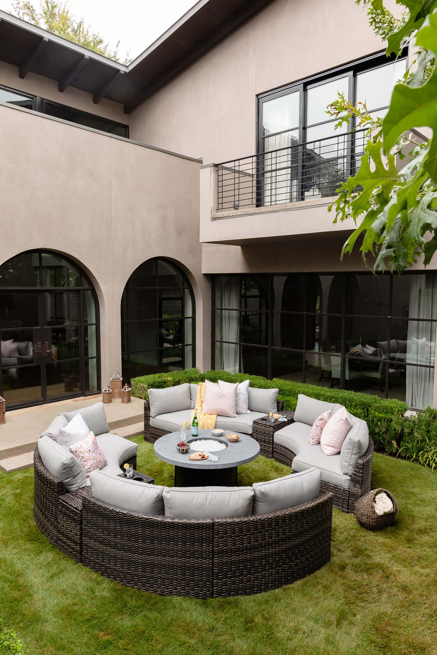 Round outdoor patio furniture with grey cushions and a round firepit in the middle.