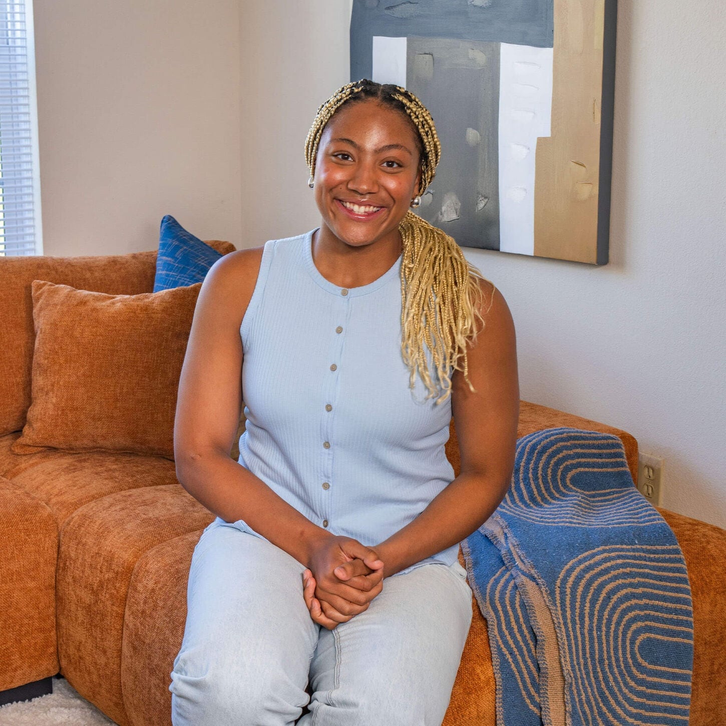TyJanae posing on her new couch in her apartment