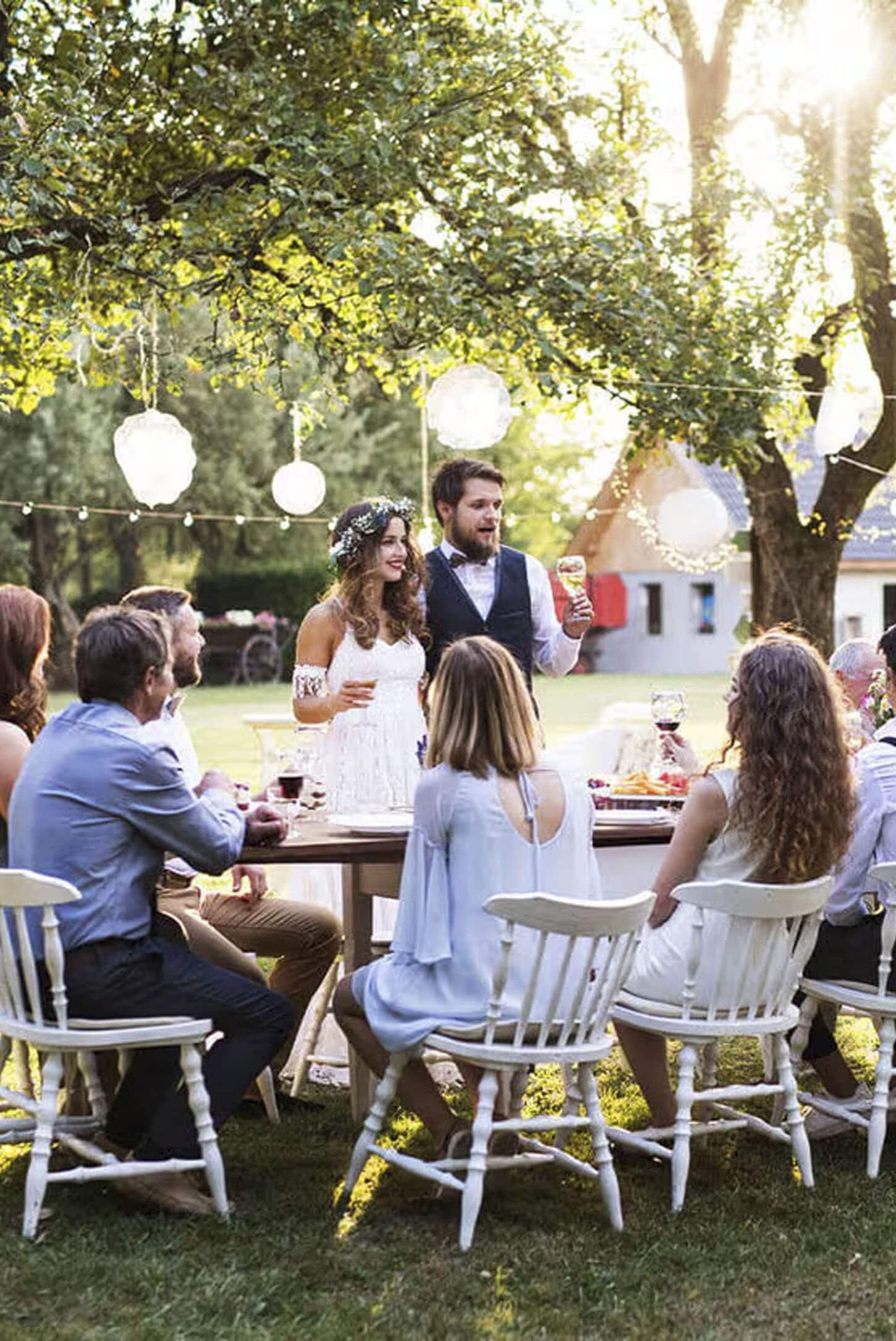 Outdoor micro wedding with bride and groom giving speech and everyone sitting at a table